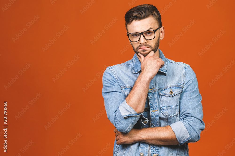 Young man in casual with dreamy cheerful expression, thinking, looking at camera, isolated on orange background. Young man in casual with dreamy cheerful expression, thinking, looking at camera, isolated on orange background.