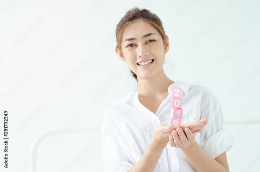 The box with the numbers in 2020, placed on a white futon and the woman's hand picked up the box.Do not focus on the main object of this image. The box with the numbers in 2020, placed on a white futon and the woman's hand picked up the box.Do not focus on the main object of this image.