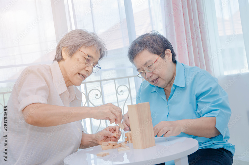 Obraz premium Asian elderly women Wearing a blue shirt And friend are playing games Have fun in the morning at home in the room.