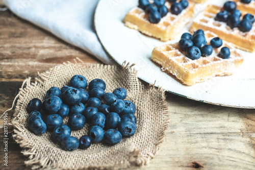a plate with waffles, dusted with powdered sugar and fresh blueberries
