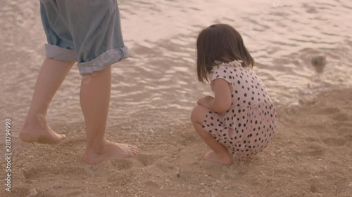 Mother with¬†daughter¬†playing on beach at sunset photo