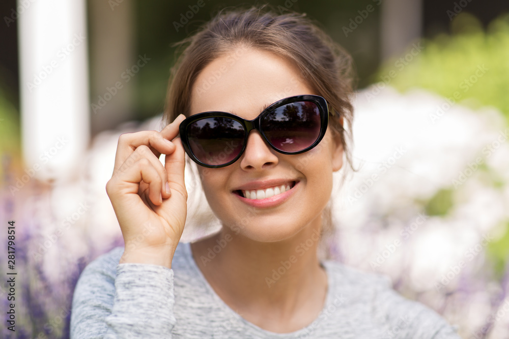 summertime, leisure and people concept - portrait of happy young woman in sunglasses at summer garden