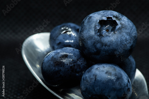 Blueberries Macro closeup photo of superimposed on top of each other and tiled in a teaspoon against a dark background.