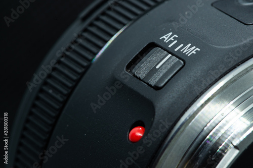 Macro closeup photo of lens to dslr camera on dark background view of red dot and silver extension ring and autofocus button.
