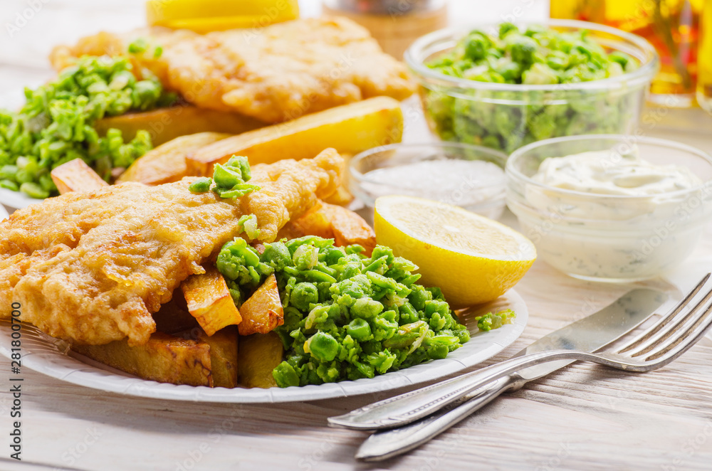 Traditional British street food fish and chips with tartar sauce and mushy peas on paper plate Traditional British street food fish and chips with tartar sauce and mushy peas on paper plate