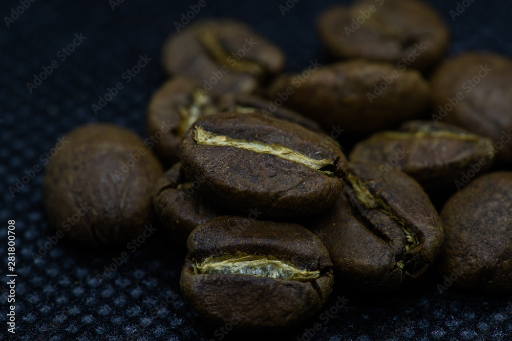 Closeup macro view of coffee beans laid on a black background after roasting in the apparatus. Closeup macro view of coffee beans laid on a black background after roasting in the apparatus.