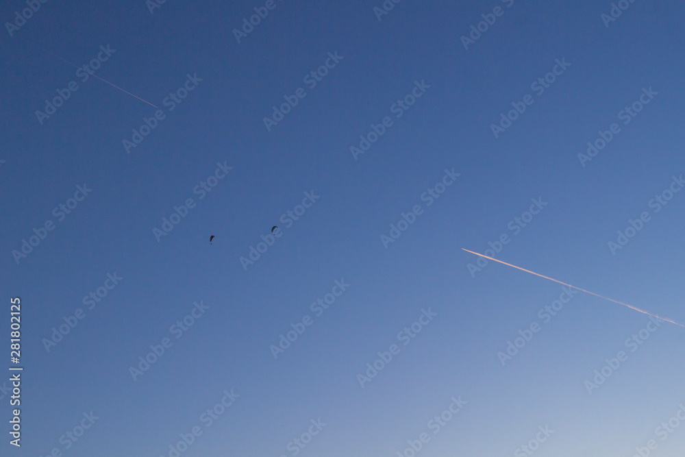 Two skydivers and two tracks from the plane against the blue sky. Two skydivers and two tracks from the plane against the blue sky.