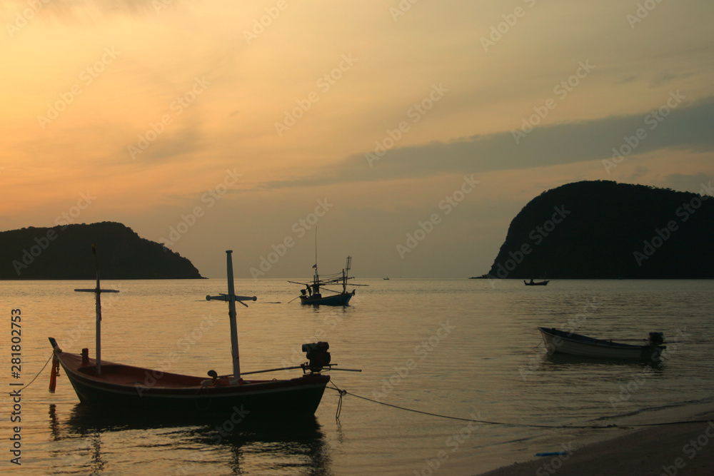 Thai fishing boat used as a vehicle for finding fish in the sea on sunset background.