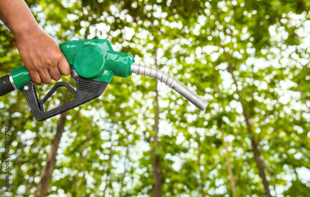 Naklejka premium Green conservation. Gas pump nozzle and leaf background. Fuel dispenser on nature background. energy conservation of Nature Concept.