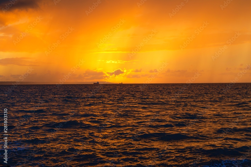 Dramatic sunset through a cloudy dark sky over the ocean.