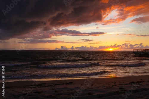 Dramatic sunset through a cloudy dark sky over the ocean. © Elena Sistaliuk