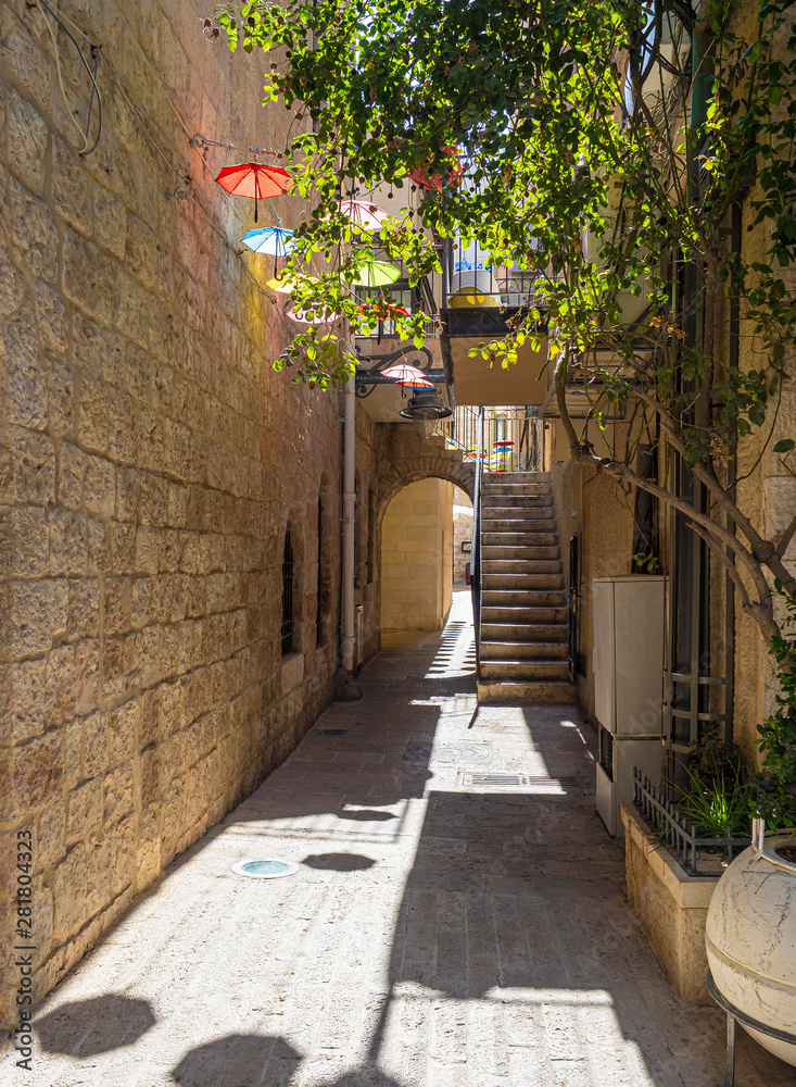 Fototapeta Latem na małym dziedzińcu w Jerozolimie są kolorowe parasole z jasnego, gorącego słońca.