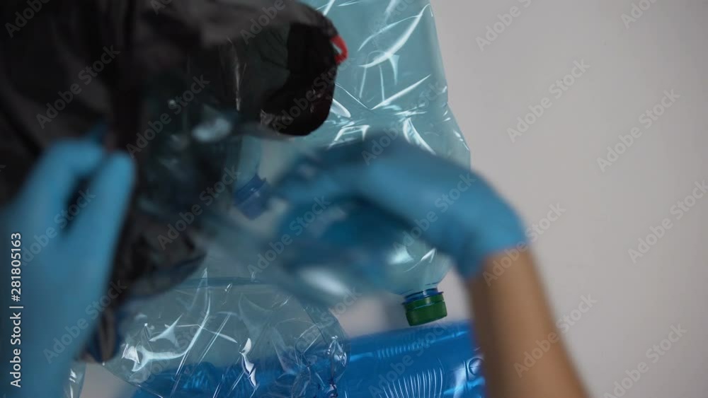 Person in gloves collecting used plastic bottles in bag, dangerous disposals Person in gloves collecting used plastic bottles in bag, dangerous disposals