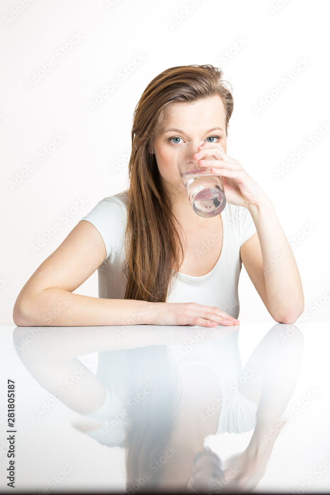 Beautiful, young woman isolated on white background with a reflection underneath her having a drink of clean, fresh water Beautiful, young woman isolated on white background with a reflection underneath her having a drink of clean, fresh water