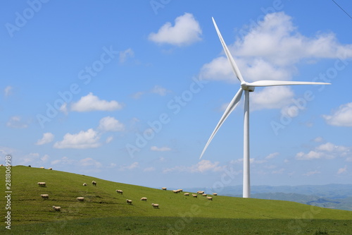 wind turbine on a green hill under a blue sky