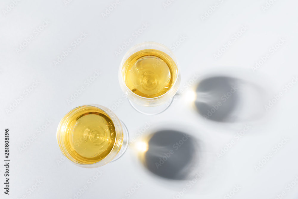 Two wineglasses of white wine with shadows on gray background. Top view. Holiday celebration concept