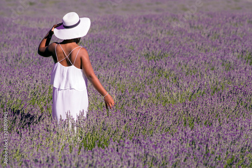 African-American woman with white dress and hat strolling between the rows of lavender in bloom
