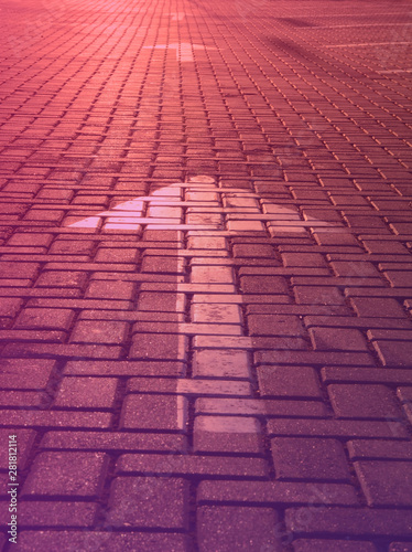 Arrow on a road tile in the rays of the setting sun on purple toned blurred background