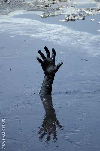 hand of a man drowning in mud