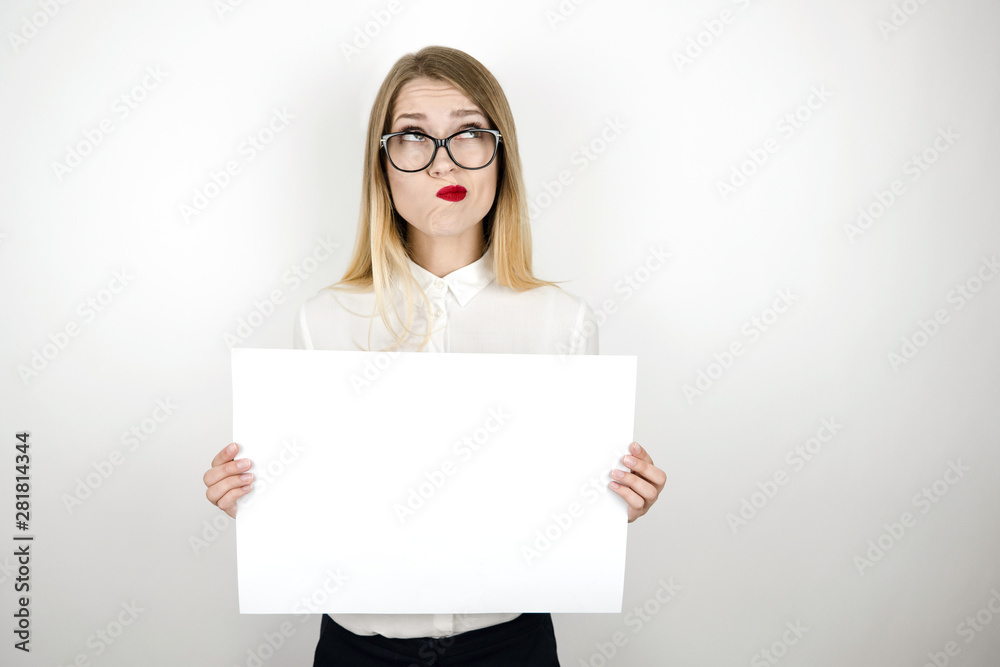 young confused business woman in eyeglasses holding blank sheet of paper for announcement isolated white background space for text