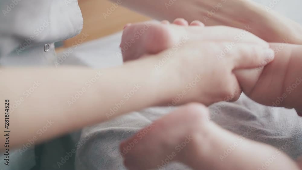 skilled pediatrician holds newborn baby small leg and practices massage actively on changing table close view skilled pediatrician holds newborn baby small leg and practices massage actively on changing table close view