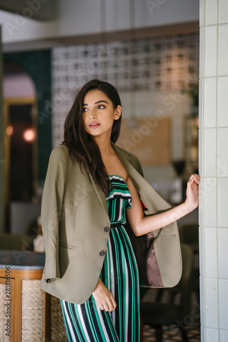 Photography Portrait of a tall, slim, elegant and beautiful Indian Asian woman in an elegant jumper with a green jacket draped over her shoulders