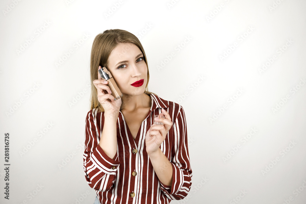 young beautiful gorgeous blonde woman wearing trendy striped shirt holding foundation cream isolated white background young beautiful gorgeous blonde woman wearing trendy striped shirt holding foundation cream isolated white background