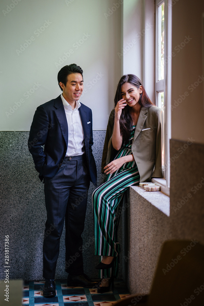 Φωτογραφία A photogenic young diverse Asian couple smiing together by the window of a well-decorated interior