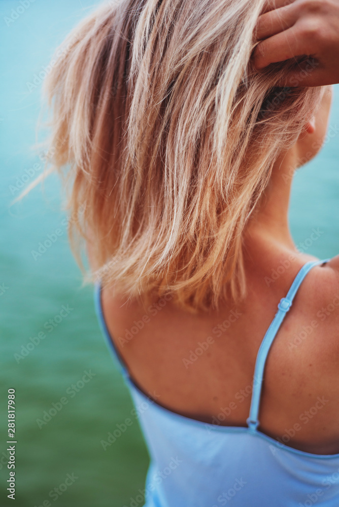 tender girl near the water, sea, river or ocean, in t-shirt with naked back