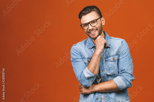 Happy young man. Portrait of handsome young man in casual shirt keeping arms crossed and smiling while standing against orange background.