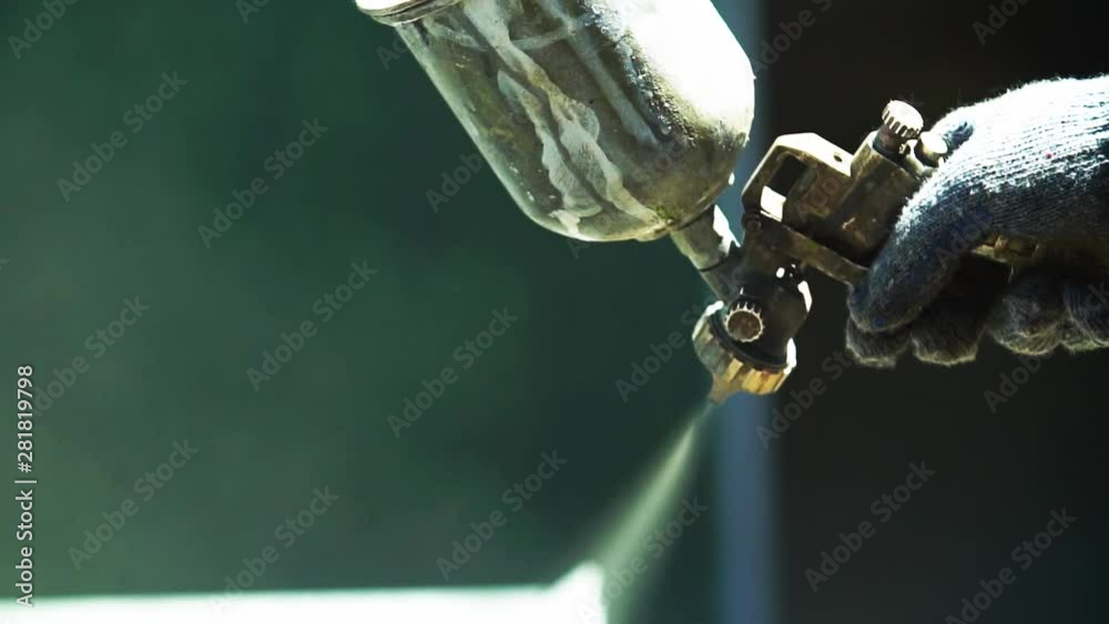 Man Paints Parts with a spray Gun. Large human hand and air spray Gun.