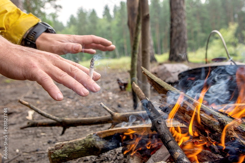man warms hands near campfire in the forest.