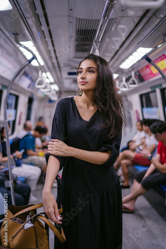Photography Portrait of a tall, slim, beautiful and attractive Indian Asian woman riding the train on her own with her luggage