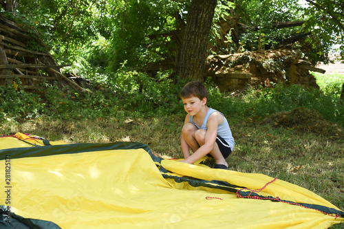 Child making tent for camping outside. Boy have fun with a tent