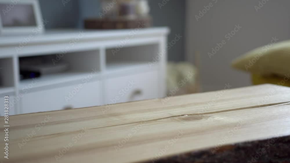 Man lifts and puts down a glass of iced coffee on the wooden table in a bright living room Man lifts and puts down a glass of iced coffee on the wooden table in a bright living room