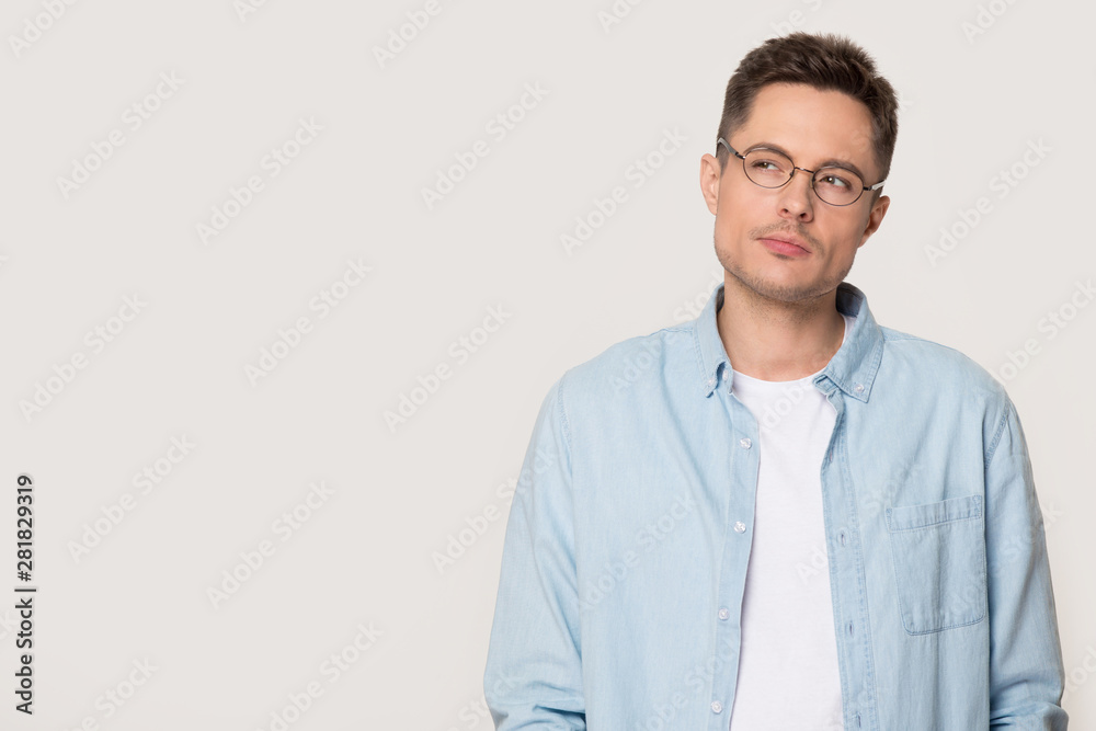 Doubting guy in glasses standing over grey white studio background Doubting guy in glasses standing over grey white studio background