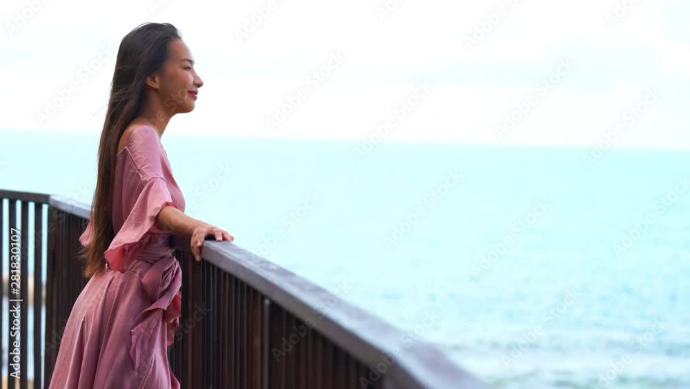 Young attractive asian woman looking at the ocean on a balcony. Young attractive asian woman looking at the ocean on a balcony.