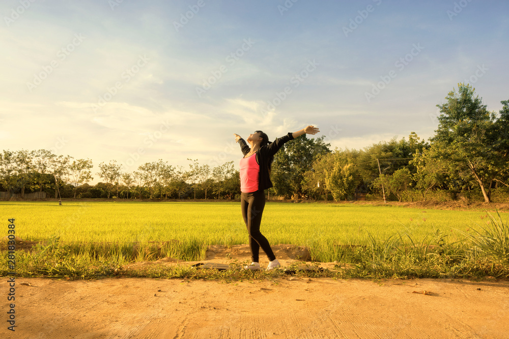 Yoga Woman feeling happy after praticing at the rice fields with sunset