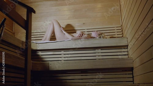 Low angle Sauna scene, beautiful woman lying topless alone 4k
