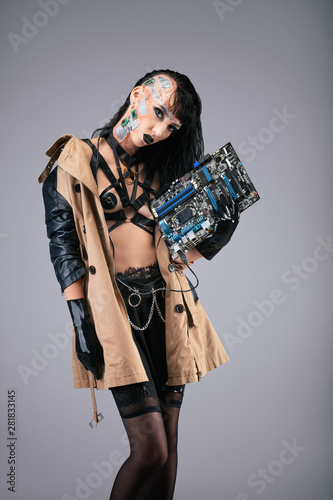 Young cyborg woman holding a motherboard