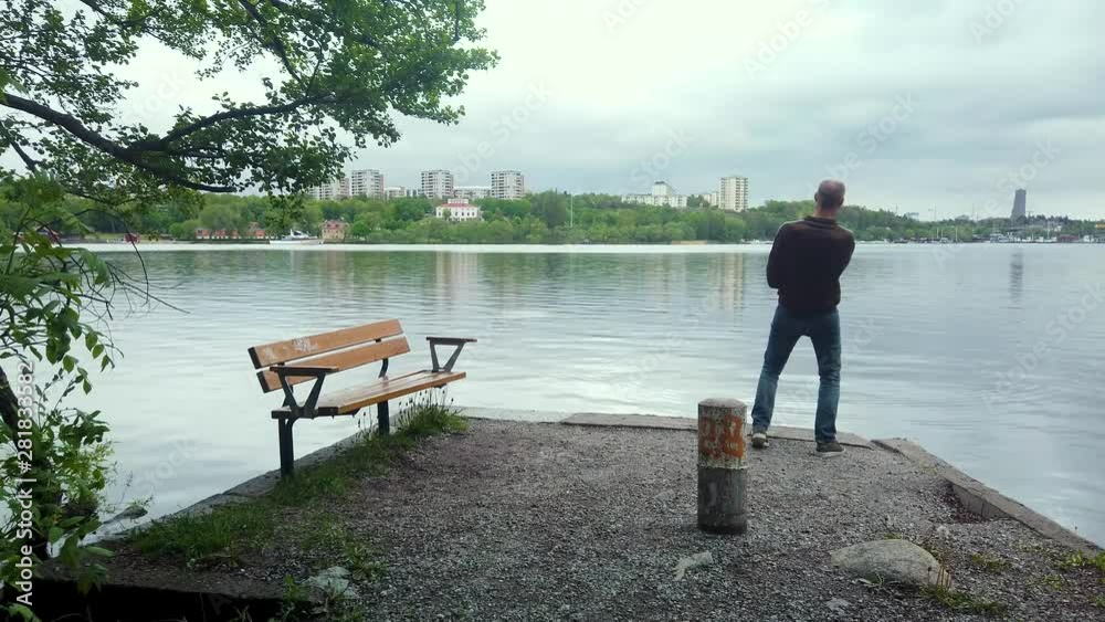 Man on pier stone skipping. Cityscape in horizon. Man on pier stone skipping. Cityscape in horizon.