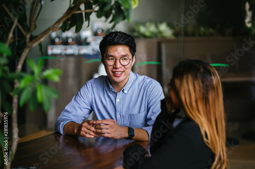 Canvas Print A young Asian business woman during a consultation with a young Korean Asian man for business advice