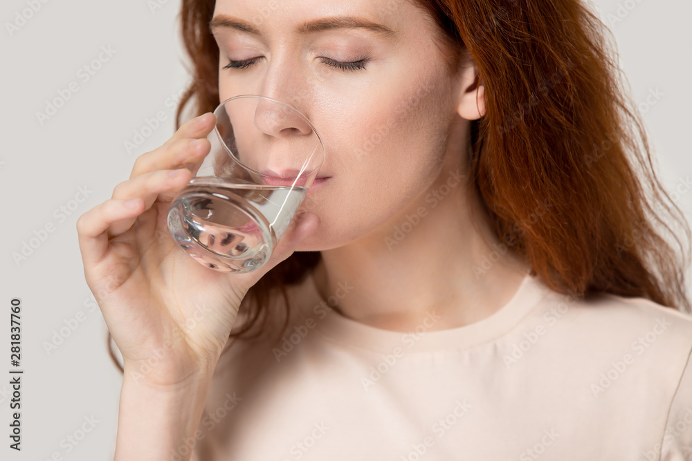 Close up young thirsty red-headed woman drinking clean water Close up young thirsty red-headed woman drinking clean water