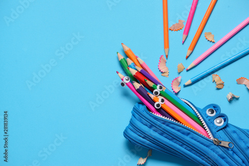 Fotografie, Obraz Funny Back to School concept - pencil case eating pencils on blue background