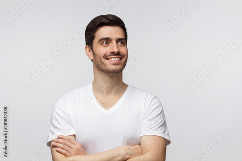 Dreaming young man looking away while standing isolated on gray background
