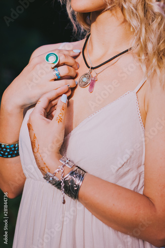 Close up of hippie young woman hands with lot of boho style jewelry, blue rings and silver bracelets. Woman hands with mehndi tattoo. Bohemian accessories. 