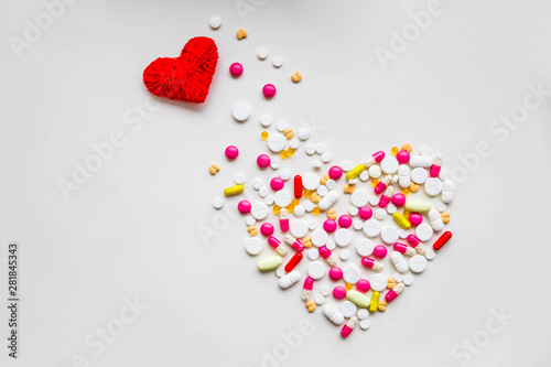 red heart with different pills over white background, healthy life concept.heart disease, heart condition. Problems with health. Arrhythmia, heart failure.impact of tablets on pregnancy.Copy space photo