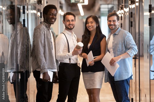 Happy multiethnic professional business team standing together in office hallway