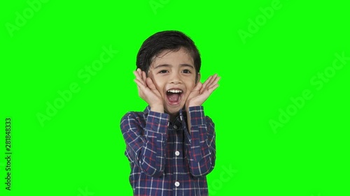 Cute little boy closing his face and playing peekaboo or hide and seek with fun in the studio. Shot in 4k resolution with green screen background