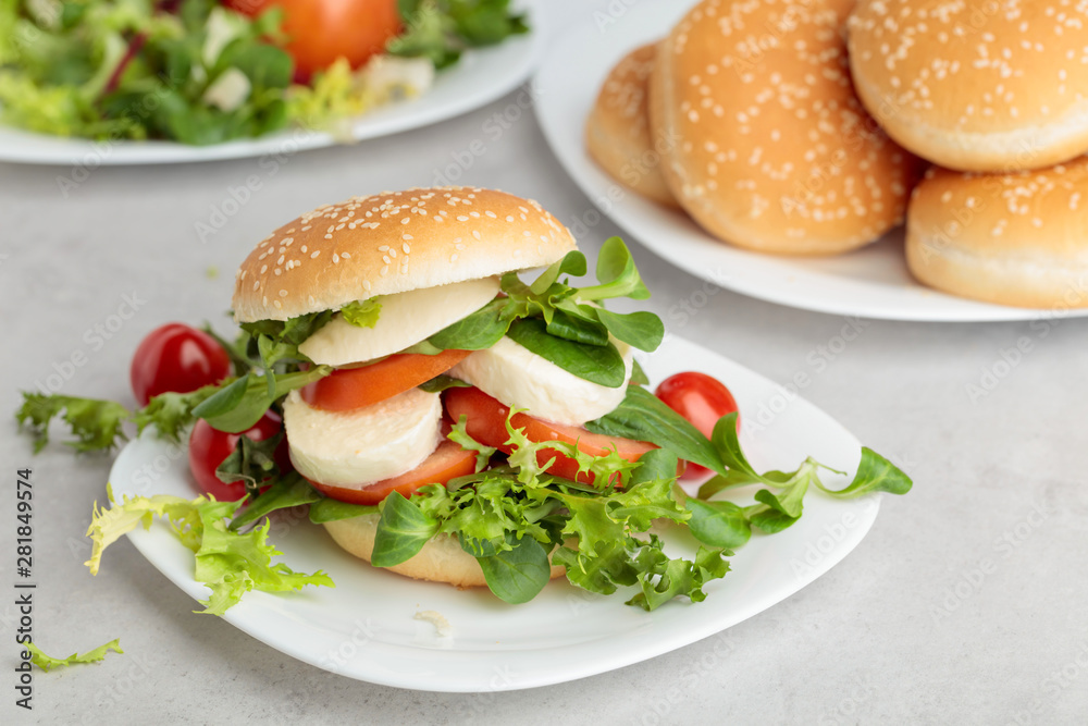 Sandwich with mozzarella, tomato and salad on the kitchen table.